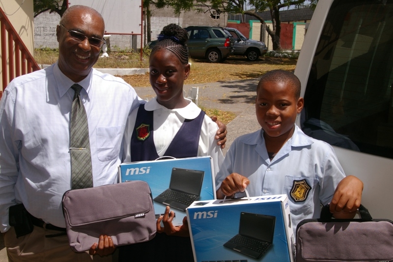 Premier of Nevis, Hon. Joseph Parry with children holding their laptops